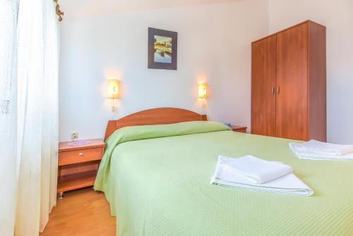 1 dormitorio con cama verde y armario de madera en Apartments Adria en Biograd na Moru