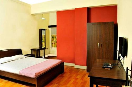 a bedroom with red walls and a bed and a desk at Bothra Guest House in Kolkata