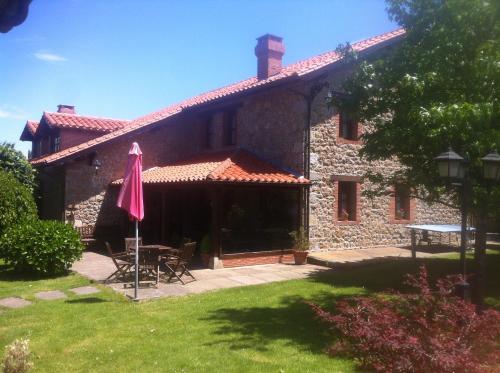 a stone house with a table and a pink umbrella at Casa Solallosa 112 in Quijas