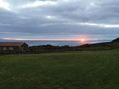 a house in a field with the sunset in the background at Pico da Vigia in Santa Bárbara