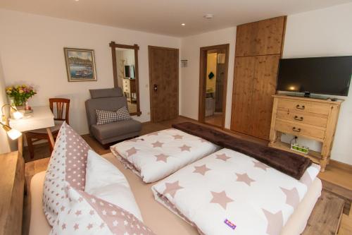 a living room with a couch and a tv at Hotel Alpenblick in Riedering