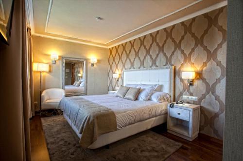 ein Schlafzimmer mit einem großen Bett und einem Spiegel in der Unterkunft Hotel Os Olivos in Guísamo