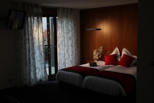 a bedroom with a bed with red pillows and a window at Hotel Au Nid De Cigognes in Ostheim
