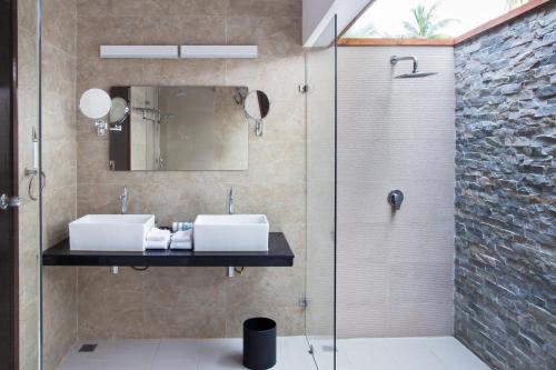 La salle de bains est pourvue de 2 lavabos et d'une douche en verre. dans l'établissement Pearl Sands of Maldives, à Atoll Malé Nord