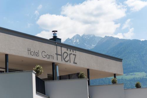 a hotel sign with mountains in the background at Hotel Garni Herz in Tirolo