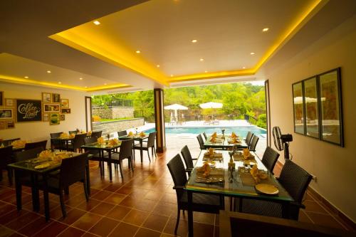 a restaurant with tables and chairs and a pool at Athirapally Green Trees in Athirappilly