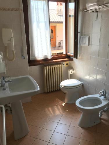a bathroom with a sink and a toilet and a window at Locanda Speranza in Torri del Benaco