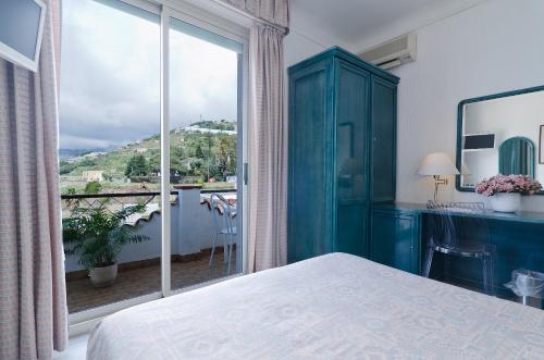 a bedroom with a blue cabinet and a large window at Hotel Ariston Montecarlo in Sanremo