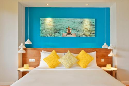 a bedroom with a bed with a blue wall at Kandima Maldives in Kudahuvadhoo