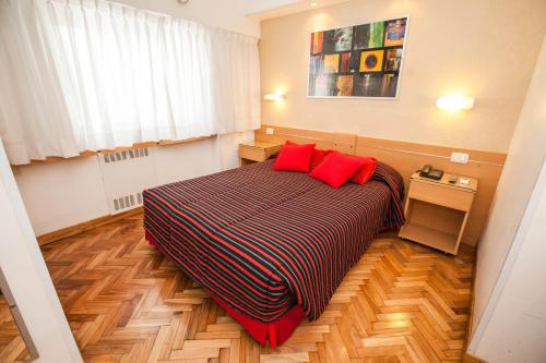 a bedroom with a bed with two red pillows at Sarmiento Palace Hotel in Buenos Aires