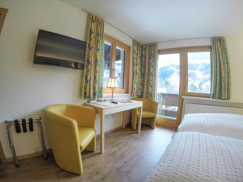ein Hotelzimmer mit einem Schreibtisch, einem Bett und einem Fenster in der Unterkunft Hotel Both in Schruns-Tschagguns