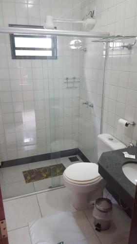 a bathroom with a toilet and a glass shower at Pousada Barcelos in São Roque de Minas