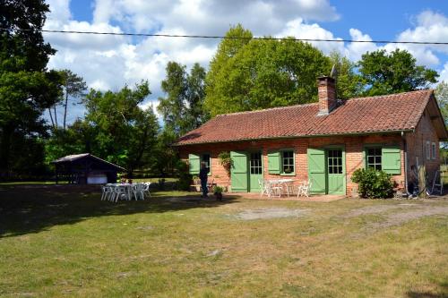 a house with tables and chairs in front of it at La Maison Ratabou in Sainte-Eulalie-en-Born