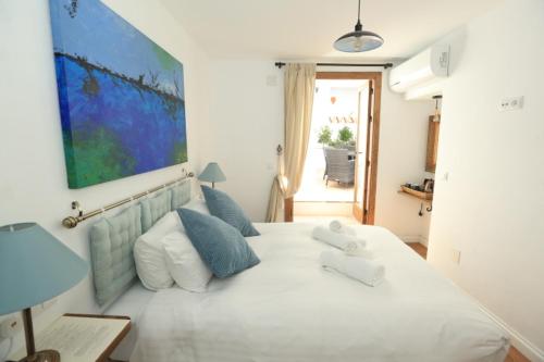 a bedroom with a large white bed with blue pillows at Casa Rural Miller's of Frigiliana in Frigiliana