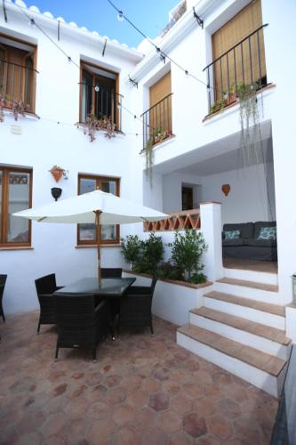 a building with a table and chairs and an umbrella at Casa Rural Miller's of Frigiliana in Frigiliana
