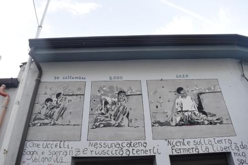 a sign on the side of a building with pictures of people at Affittcamere Jannas in Orgosolo
