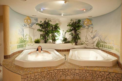 a person laying in a bath tub in a room at Hotel Reitzentrum Hausruckhof in Ampflwang im Hausruckwald