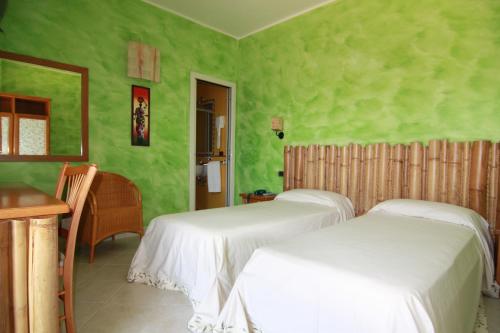 duas camas num quarto com paredes verdes em Levante Hotel em San Domino