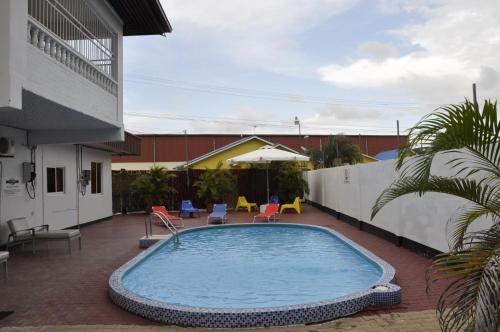 a swimming pool in a courtyard with chairs and a building at Riando appartement in Paramaribo