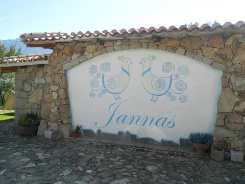 two birds on a sign on a stone wall at Affittcamere Jannas in Orgosolo