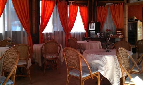 uma sala de jantar com mesas e cadeiras e cortinas vermelhas em Levante Hotel em San Domino