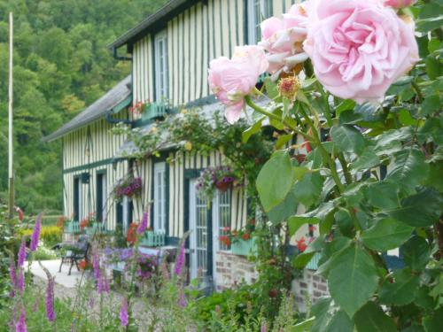 a house with pink roses in front of it at Chambre d'hôtes Au Fil De L'eau in Jumièges