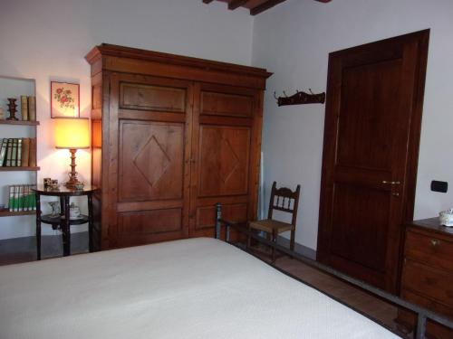a bedroom with a bed and a cabinet and a chair at Podere Sammonti in Monteriggioni