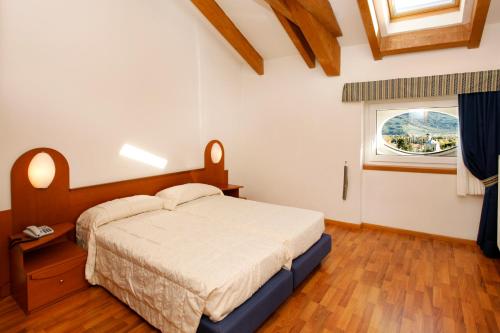 1 dormitorio con cama y ventana en Aparthotel Englovacanze, en Riva del Garda