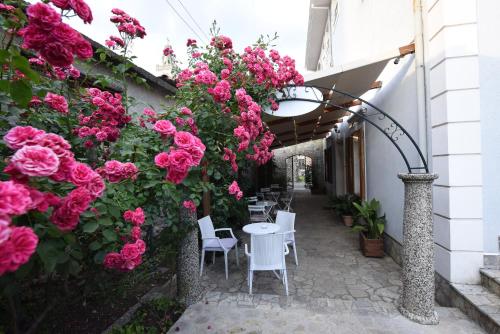 a patio with pink roses and a table and chairs at Rose Garden Hotel in Shkodër