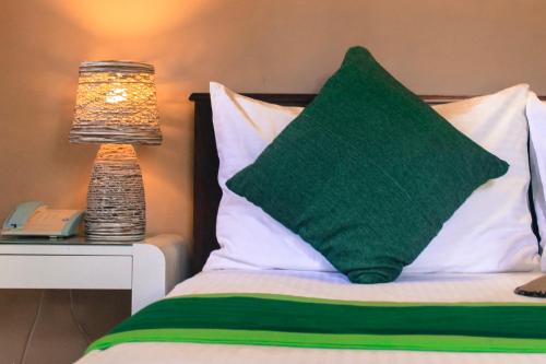 a bed with a green pillow and a lamp on a table at Airport Green Olive Villa in Katunayaka