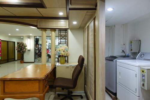 a kitchen with a desk and a table in a room at Nice Palace Hotel in Bangkok