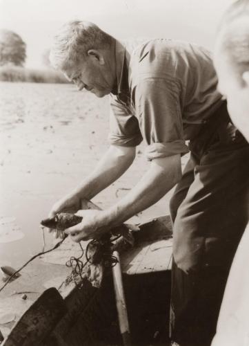 a man standing on a boat holding a crab at Gasthof Fischerstüberl in Rottau