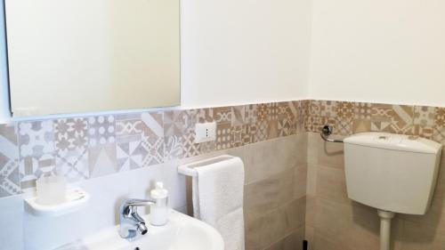 a bathroom with a sink and a toilet and a mirror at U'Cuntu affittacamere in Favignana