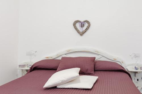 マッサ・ルブレンセにあるLa Casa di Nonna Elviraのベッド(白い枕、壁にハート付)