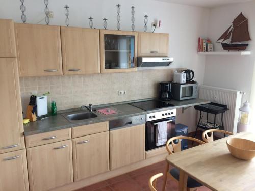 a kitchen with wooden cabinets and a sink and a table at Wohnung Bernstein - Nr. 4 in Dierhagen