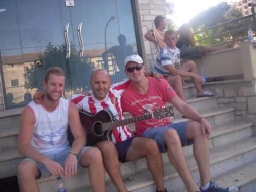 three men sitting on the steps with a guitar at Saranda Backpackers in Sarandë