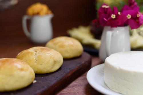un tavolo con panini e una torta su un tagliere di Pousada Casa do Catavento a Búzios