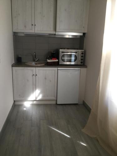 a small kitchen with a microwave and a sink at Kochyli Hotel in Spetses