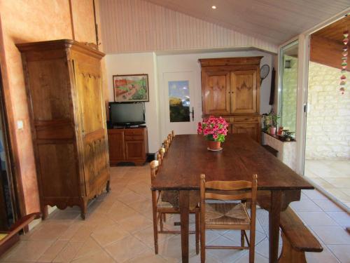 une salle à manger avec une table en bois et des fleurs. dans l'établissement La Piaule, à Saint-Pierre-le-Vieux