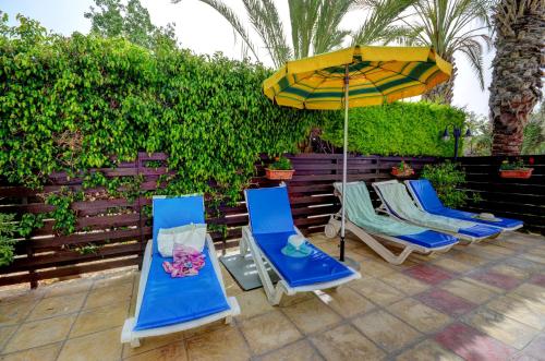 two lounge chairs and an umbrella on a patio at Renos Apartments in Polis Chrysochous