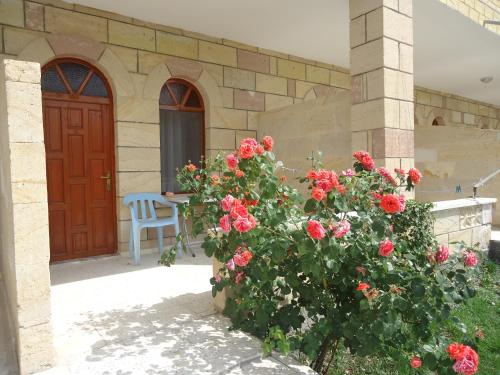 a house with a red door and a bush with red roses at Akar Hotel in Ihlara