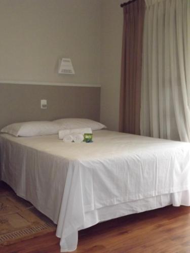 a bedroom with a white bed with white sheets and a window at Edelweiss Pomerode in Pomerode