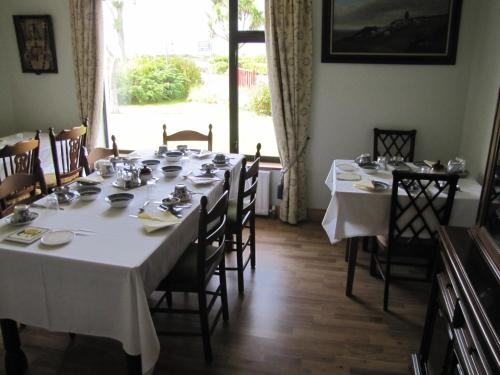 un comedor con una mesa larga con manteles blancos en An Dooneen, The Hurley Farm B&B, en Ballydavid