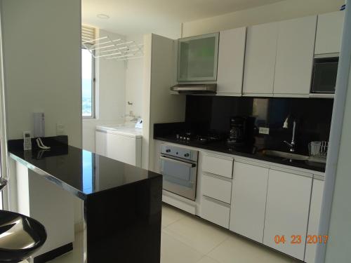 a kitchen with white cabinets and a black counter top at Tayrona Beach Bello Horizonte in Santa Marta
