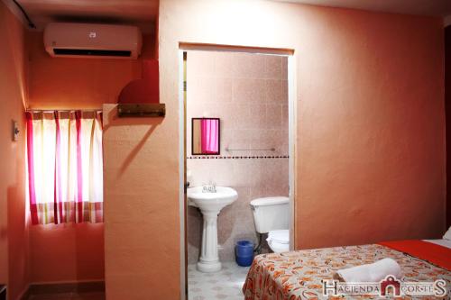 Hotel Hacienda Cortes في ميريدا: حمام به سرير ومغسلة ومرحاض