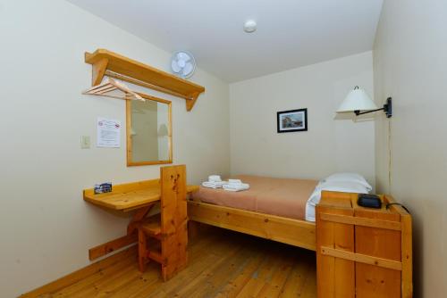 1 dormitorio con cama de madera con espejo y escritorio en The Bunkhouse, en Dawson City