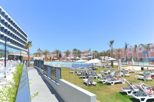 a resort with a pool and lounge chairs and people at Dos Playas - 30º hotels in Puerto de Mazarrón