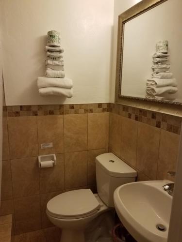 y baño con aseo, lavabo y toallas. en Scottish Inn - Okeechobee, en Okeechobee