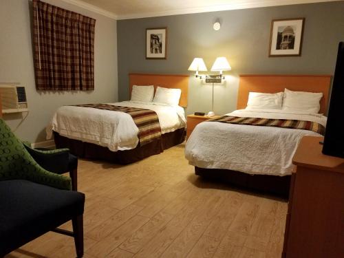 a hotel room with two beds and a chair at Scottish Inn - Okeechobee in Okeechobee