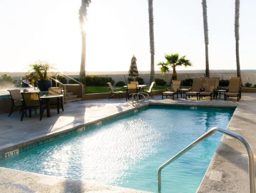 una piscina con sillas y mesas en un complejo en The Portofino Hotel & Marina, a Noble House Hotel, en Redondo Beach